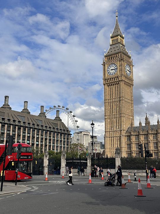 Big Ben and the Houses of Parliament in London, with a red double-decker bus and the London Eye behind