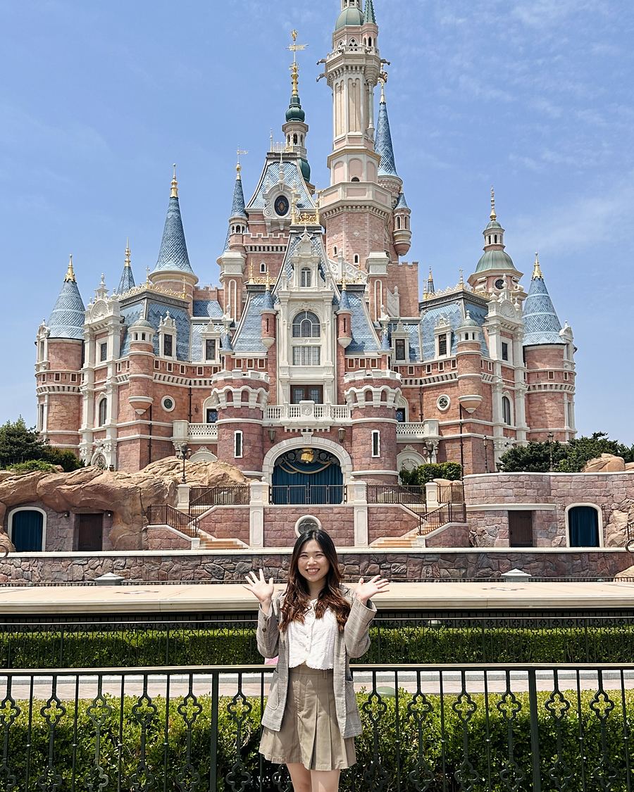 Ivy with both hands raised in front of the castle at Shanghai Disneyland